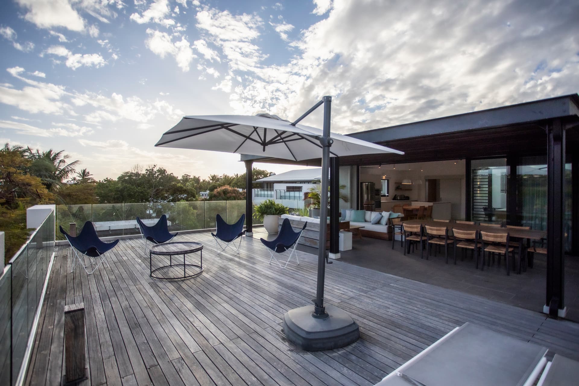 Espace extérieur avec fauteuils confortables et table basse centrale. 

Parasol offrant de l'ombre pour profiter des journées ensoleillées. 

Terrasse en bois favorisant une ambiance conviviale et détendue. 

Vue dégagée sur la nature environnante ajoutant une dimension paisible. 

Mobilier en bois créant une atmosphère chaleureuse et accueillante.