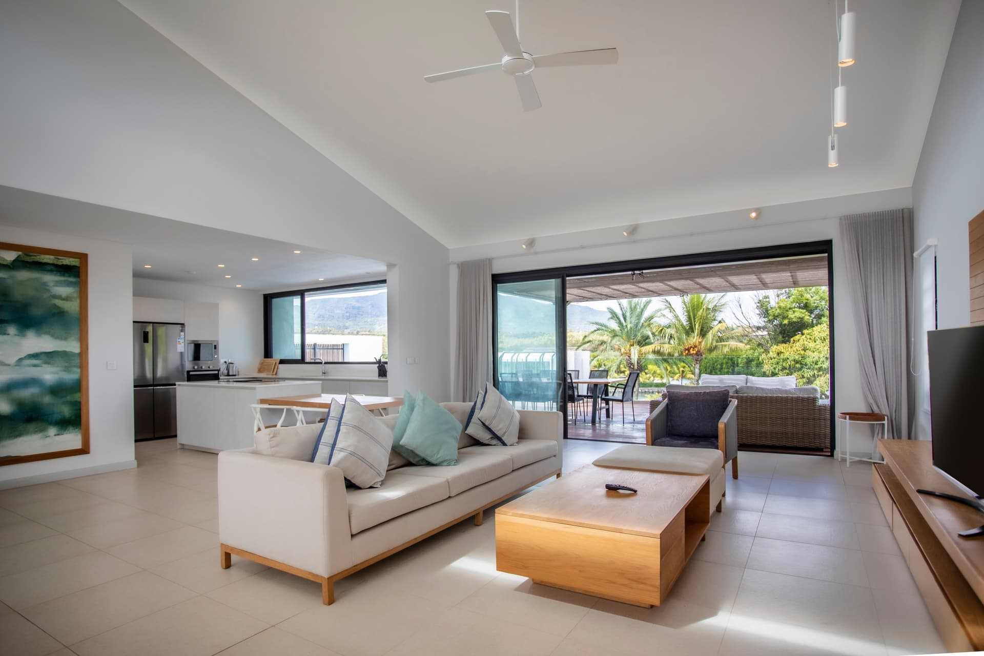 Lumière naturelle pénétrant par de grandes baies vitrées offrant une vue sur l'extérieur.  
Espace de vie ouvert intégrant un coin salon et une cuisine moderne.  
Mobilier clair et sobre créant une atmosphère fonctionnelle et contemporaine.  
Plafond haut accentuant la sensation d'espace et de luminosité.  
Accès direct à la terrasse pour prolonger