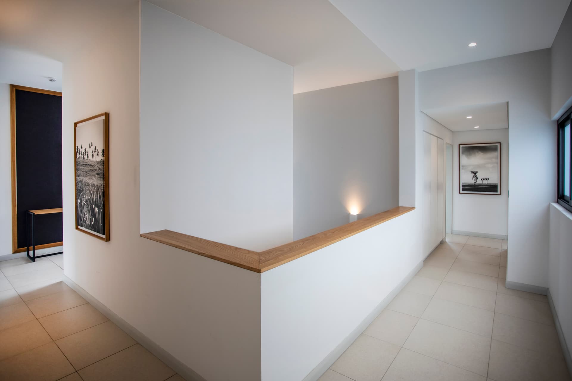 Couloir lumineux avec murs blancs et finition en bois.  
Accès direct aux différentes pièces du penthouse.  
Éclairage intégré soulignant l'espace et les lignes épurées.  
Sol carrelé apportant une touche moderne à l'agencement.  
Détails architecturaux simples créant une ambiance sereine.