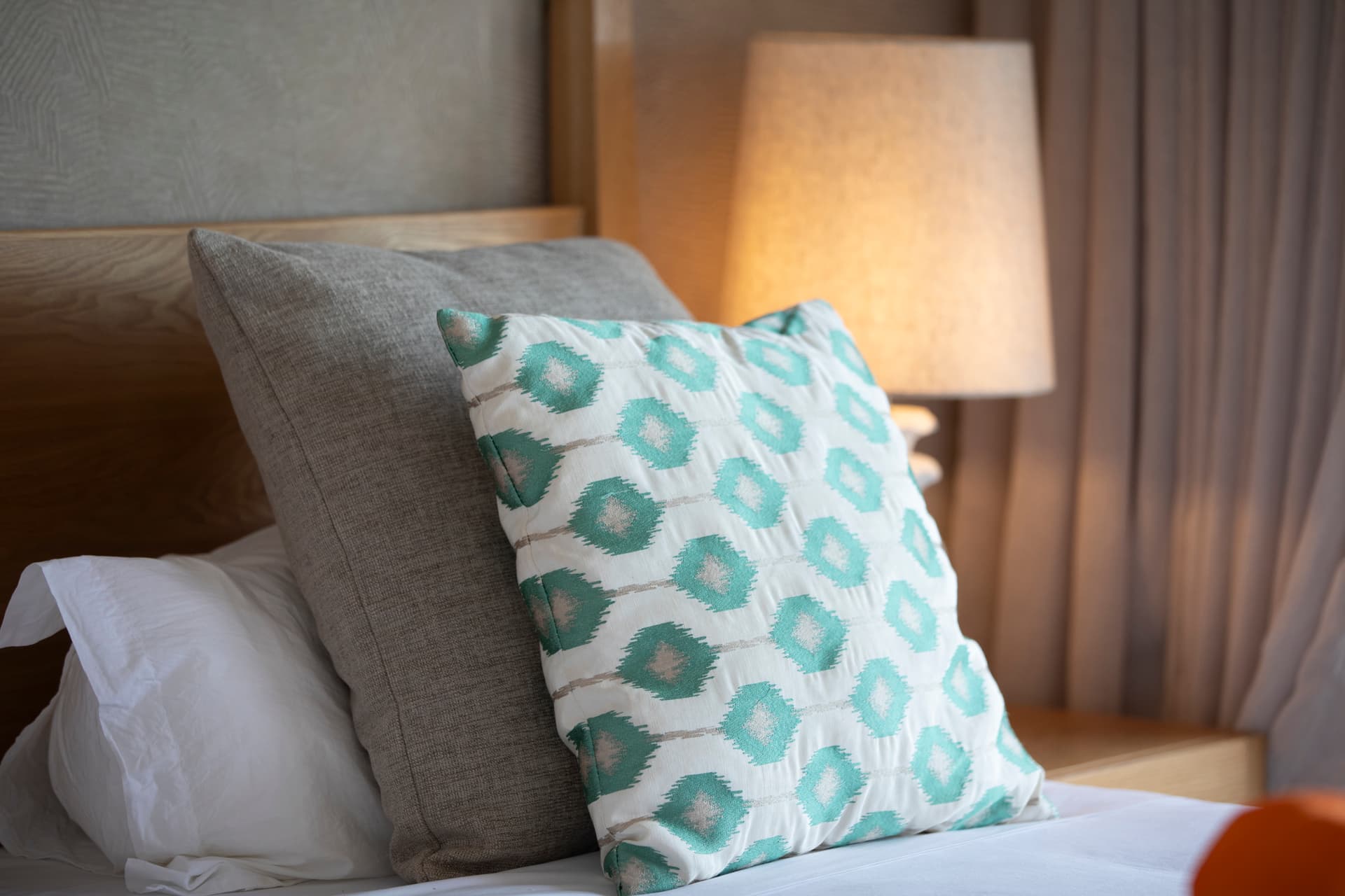 Chambre avec lit spacieux et coussins décoratifs pour un confort visuel.  
Lampe de chevet offrant une lumière douce pour une ambiance chaleureuse.  
Tons neutres dans la décoration créant une atmosphère apaisante.  
Détails textiles variés ajoutant une texture agréable à l'espace.  
Mobilier en bois clair apportant une touche naturelle à la chambre.