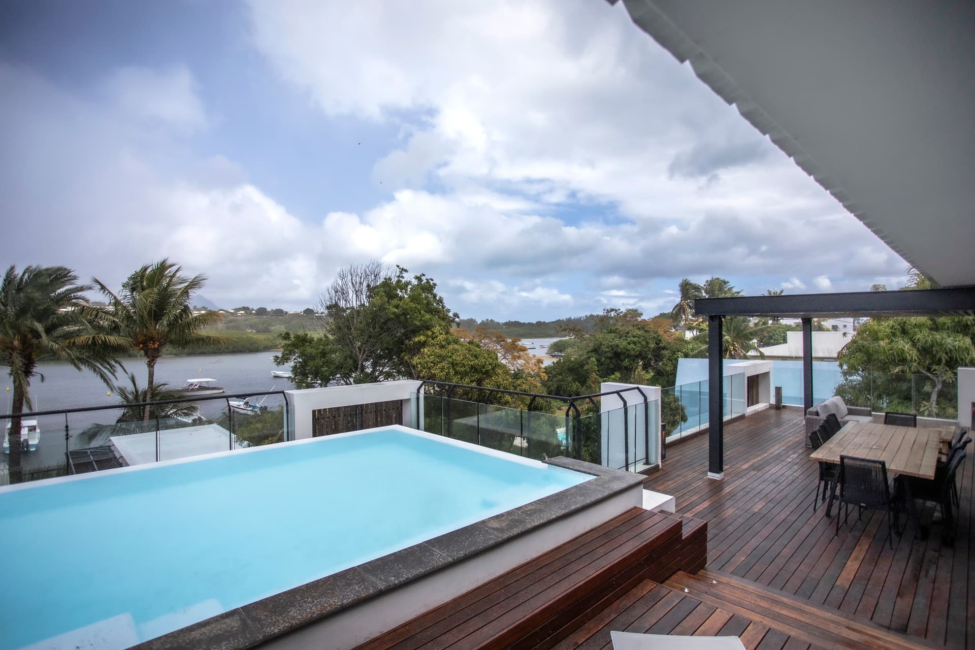 Espace extérieur avec piscine, offrant une vue sur la végétation environnante.  
Terrasse en bois équipée d'une table pour des repas en plein air.  
Chaises longues intégrées au bord de la piscine pour se détendre.  
Accès direct à la terrasse depuis le salon, facilitant la circulation.  
Végétation luxuriante encadrant l'espace extérieur, créant