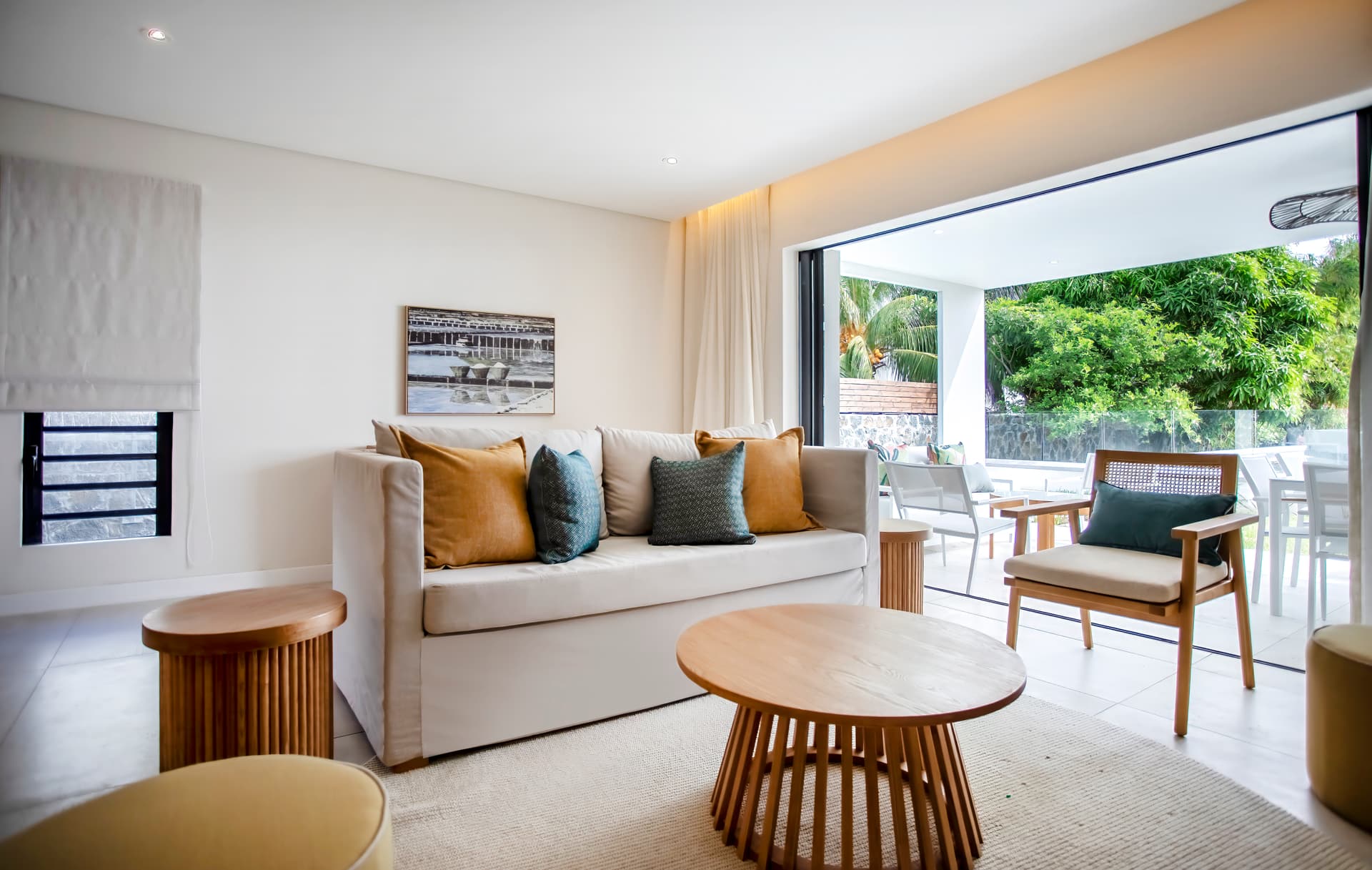 Tons clairs prédominants dans le salon, créant une ambiance apaisante.  
Espace ouvert avec accès direct à la terrasse et au jardin.  
Mobilier moderne disposé autour d'une table basse en bois.  
Lumière naturelle inondant la pièce grâce aux grandes baies vitrées.  
Coin salon confortable avec vue sur l'extérieur verdoyant.