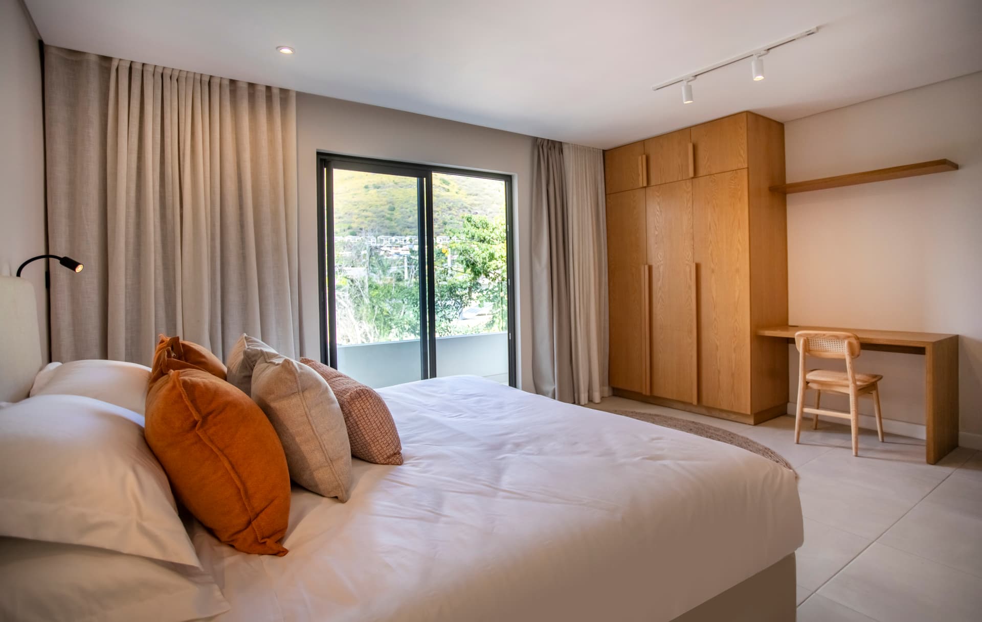 Chambre avec lit double, dotée d'une fenêtre offrant une vue dégagée.  
Mobilier en bois clair et rangements optimisés ajoutent fonctionnalité.  
Éclairage moderne au-dessus du lit pour une atmosphère agréable.  
Tapis texturé apportant une touche de confort au sol.  
Coin bureau minimaliste intégré pour un espace de travail pratique.