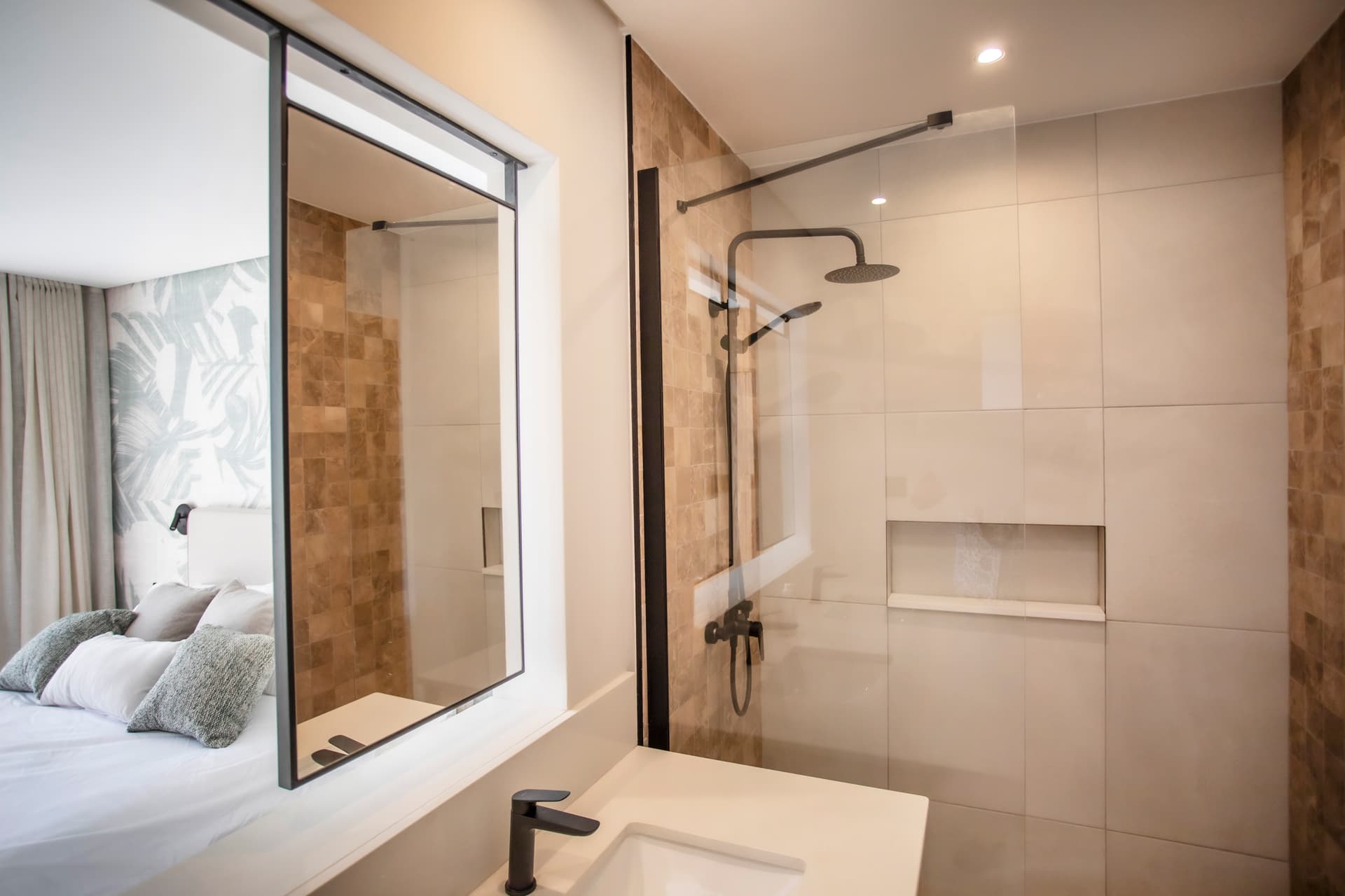 Salle de bain contemporaine avec douche à l'italienne et paroi en verre.  
Mobilier en bois clair offrant un espace de rangement pratique.  
Miroir large au-dessus du lavabo pour une meilleure visibilité.  
Éclairage intégré assurant une luminosité uniforme dans l'espace.  
Fenêtre laissant entrer la lumière naturelle et vue sur l'extérieur.