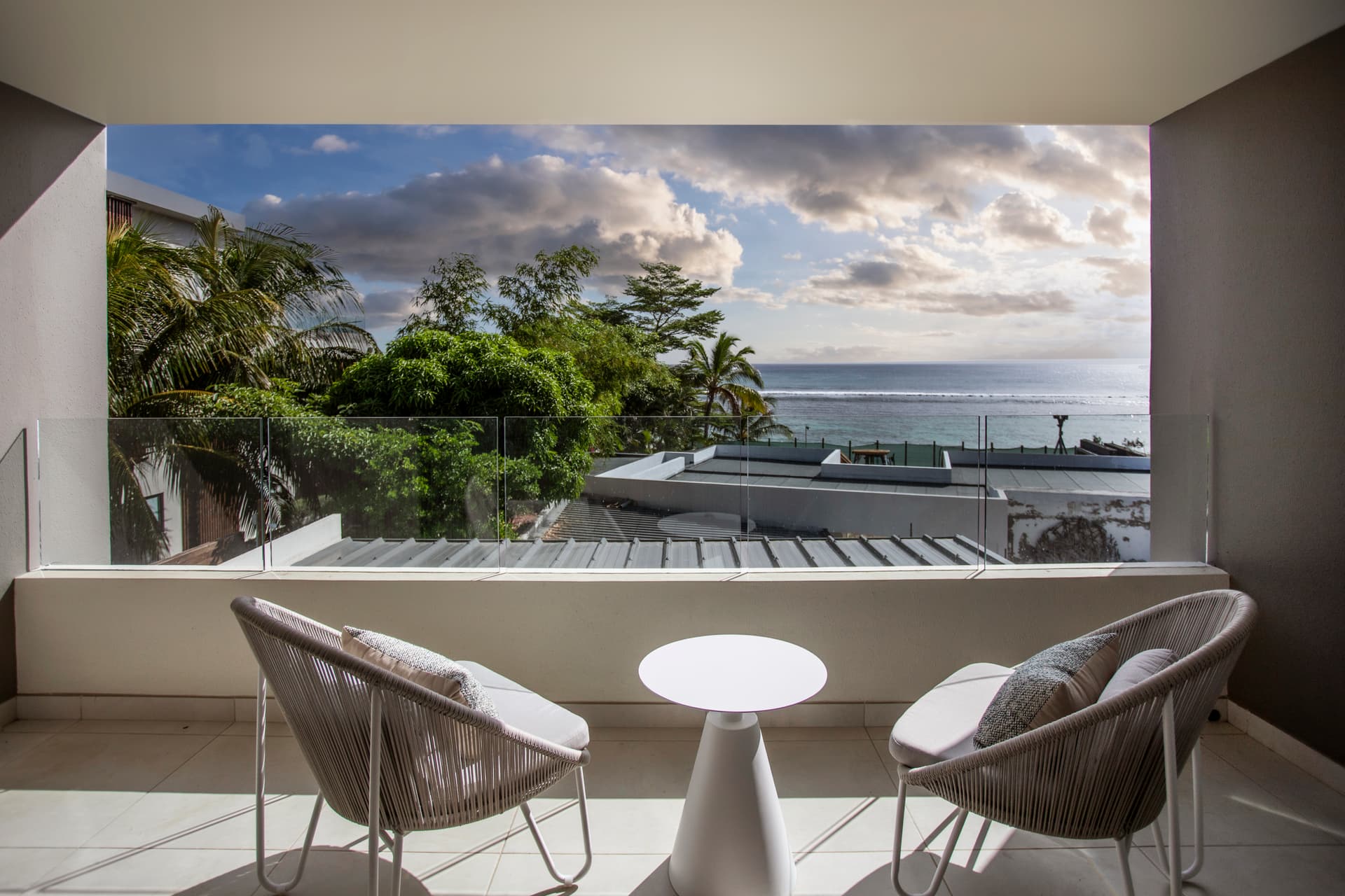 Balcon spacieux avec vue sur l'océan et mobilier confortable.  
Végétation environnante ajoutant une touche de verdure à l'espace.  
Grandes baies vitrées permettant une luminosité naturelle abondante.  
Espace extérieur propice à la détente avec une vue dégagée.  
Chaises modernes offrant un confort pour profiter de la vue.