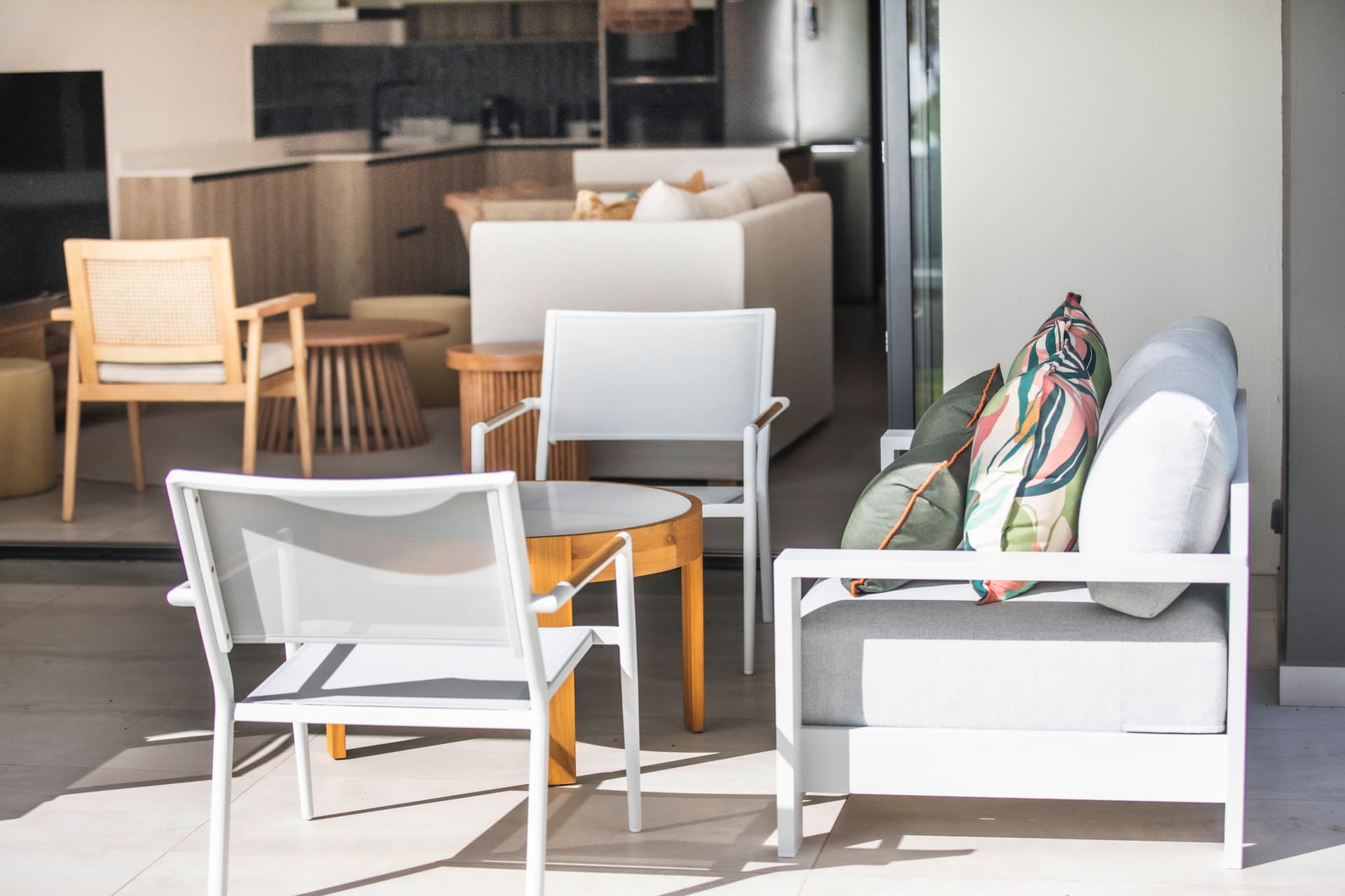 Espace extérieur avec mobilier moderne en rotin et coussins colorés.  
Vue sur l'intérieur grâce aux grandes baies vitrées.  
Coin salon confortable propice à la détente.  
Éclairage naturel créant une ambiance accueillante dans l'espace.  
Détails décoratifs ajoutant une touche de style contemporain.