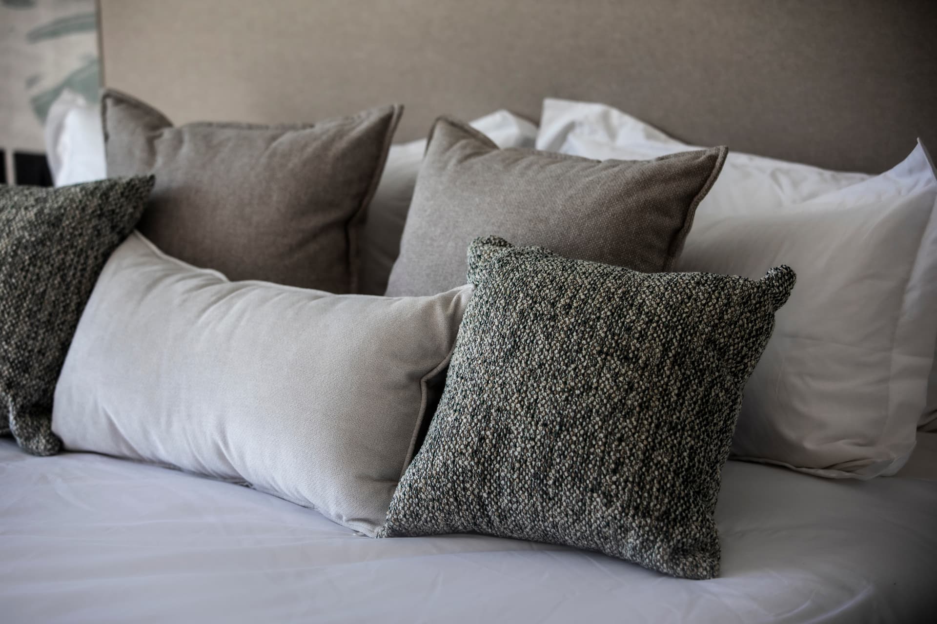 Textures douces sur des coussins assortis, apportant confort et élégance.  
Harmonie de couleurs neutres créant une atmosphère apaisante dans la chambre.  
Coussins de différentes tailles ajoutent une dimension visuelle au lit.  
Éclairage subtil mettant en valeur les détails des textiles.  
Agencement réfléchi favorisant la détente et le repos.